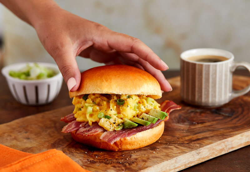 Autumn Burger Recipe Ideas: a hand placing the top of a burger bun on a burger on a wooden board