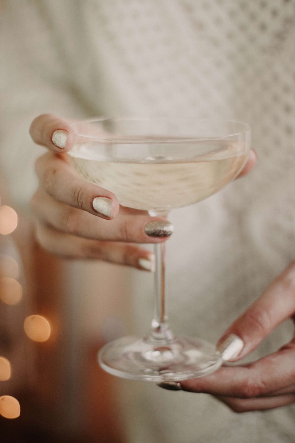 A close up of a woman holding a glass of champagne in both hands