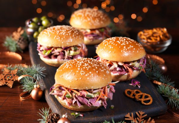 A photo of St Pierre Seeded Brioche Burger Buns filled with ham hock and winter slaw on a serving board