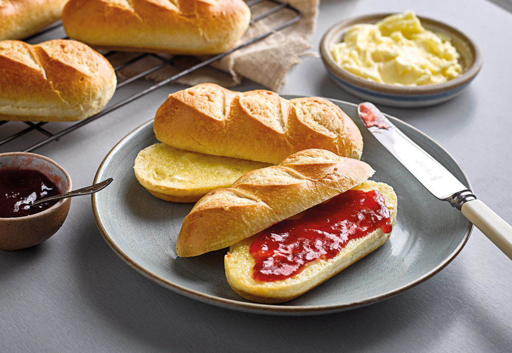 Two St Pierre Brioche Rolls sliced in half, with one filled with strawberry jam